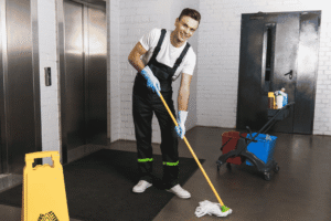 A person in overalls mopping a floor