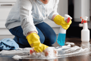 A person cleaning a wooden floor with a sponge.