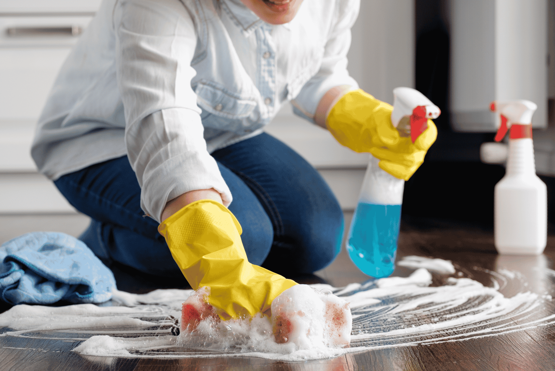 A person cleaning a wooden floor with a sponge.